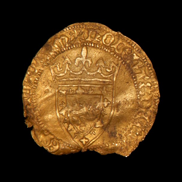 A cold coin with crumpled edges. The centre of the coin shows a coat of arms with an indistinct image in the centre. A crown sits on top of the shield.